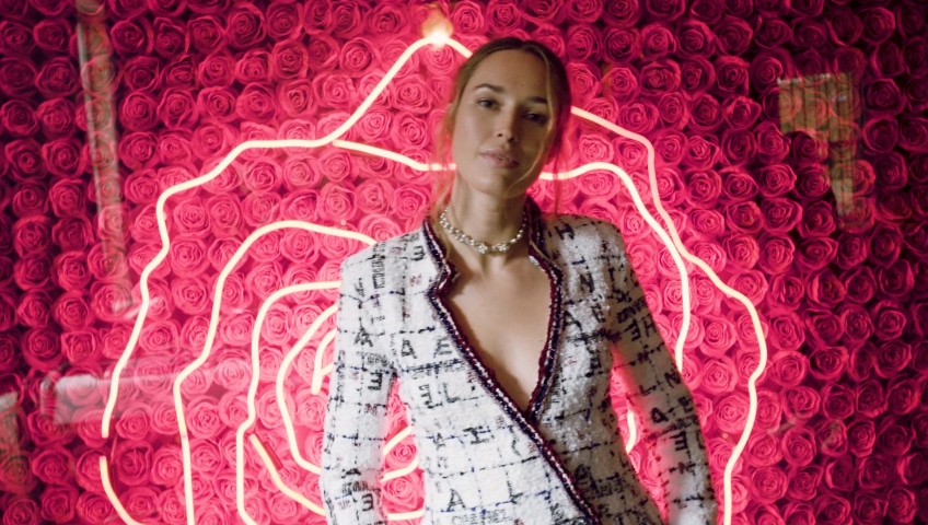 Lady dressed in white suit in front of red neon light pattern